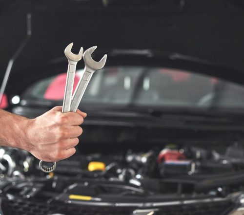 Mechanic holding pair of wrenches at the repair garage