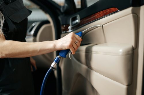 Woman cleaning car salon with polishing spray in car detailing service